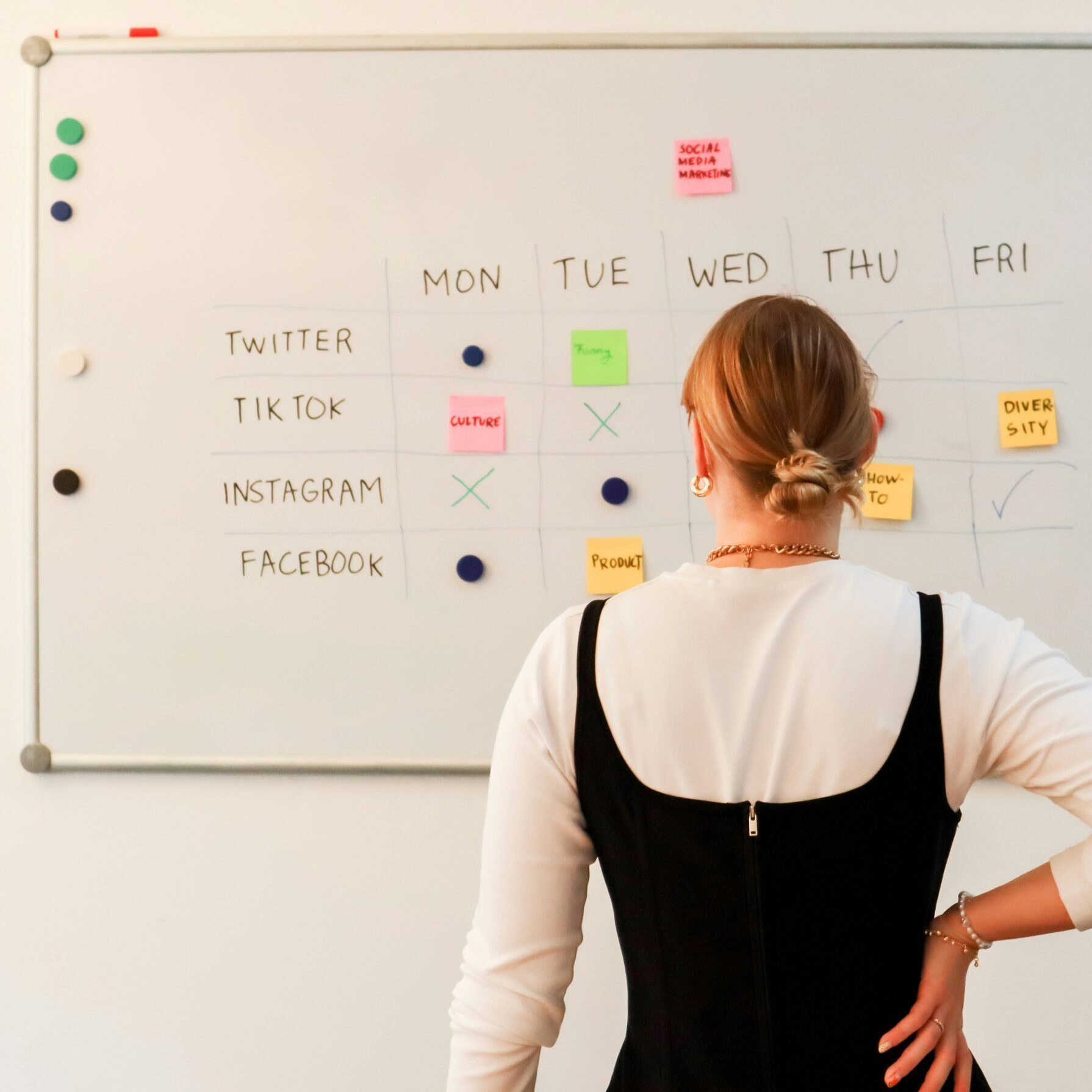 A woman stands in front of a white board with social media ideas. 